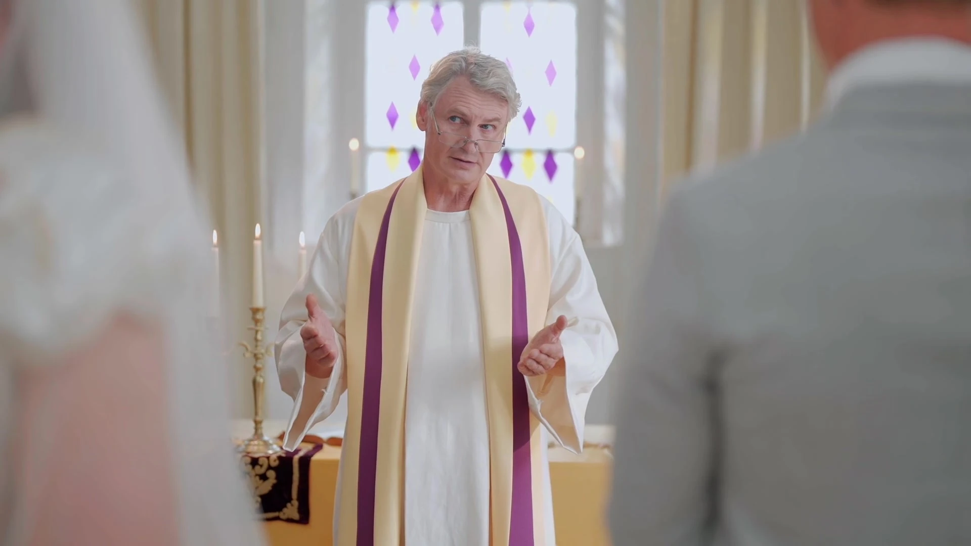 Kunigas ceremonijoje, jaunavedžiai kadro kraštuose.